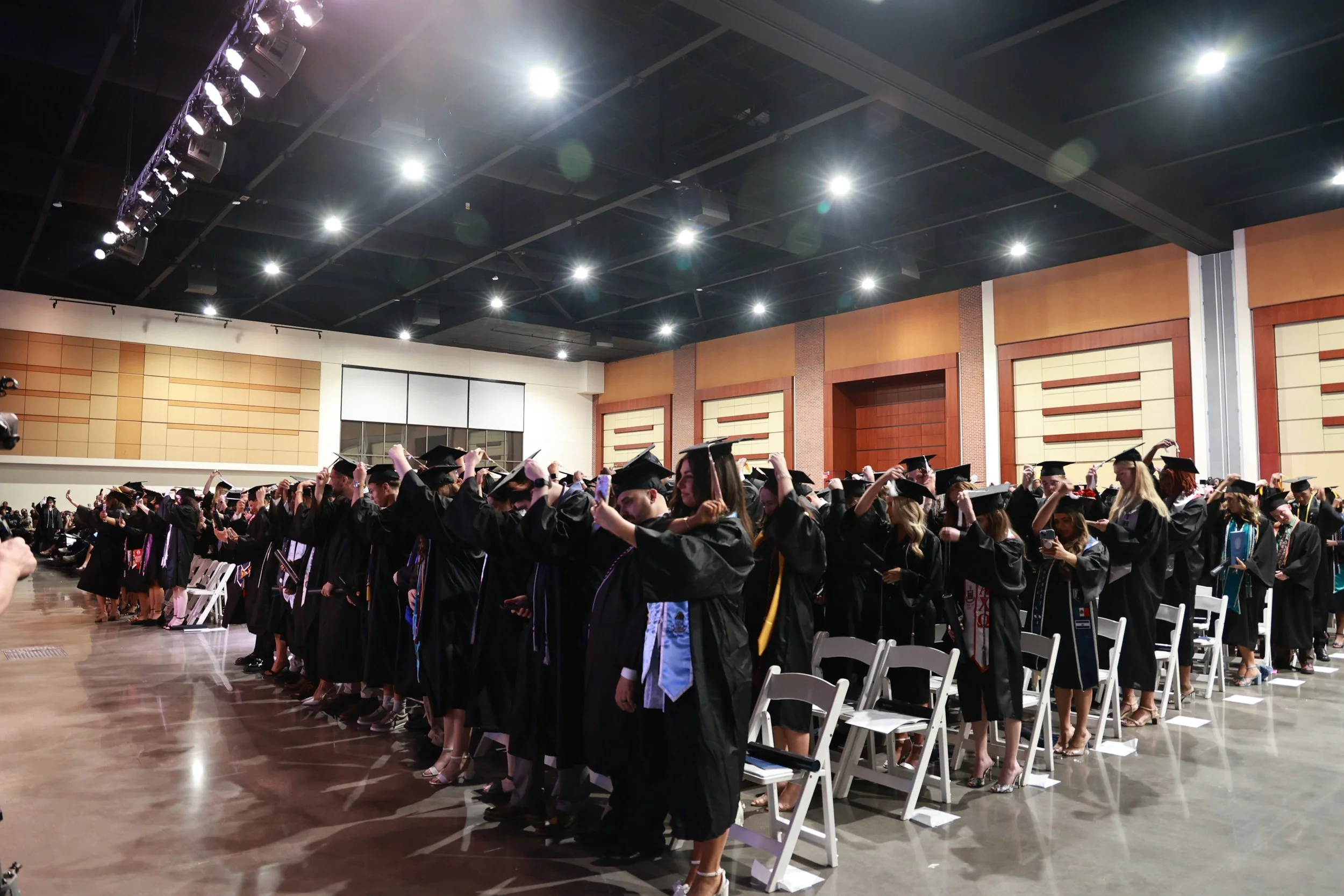  Augusta University undergraduate students move their tassels to the left after hearing from Kyle Scott, president of the Summerville Alumni Society. At the top of the page, Vera Stewart talks about her childhood where she learns to work hard and be creative. (photos by Rodrigo J. Burgos-Avila/the Bell Ringer) 