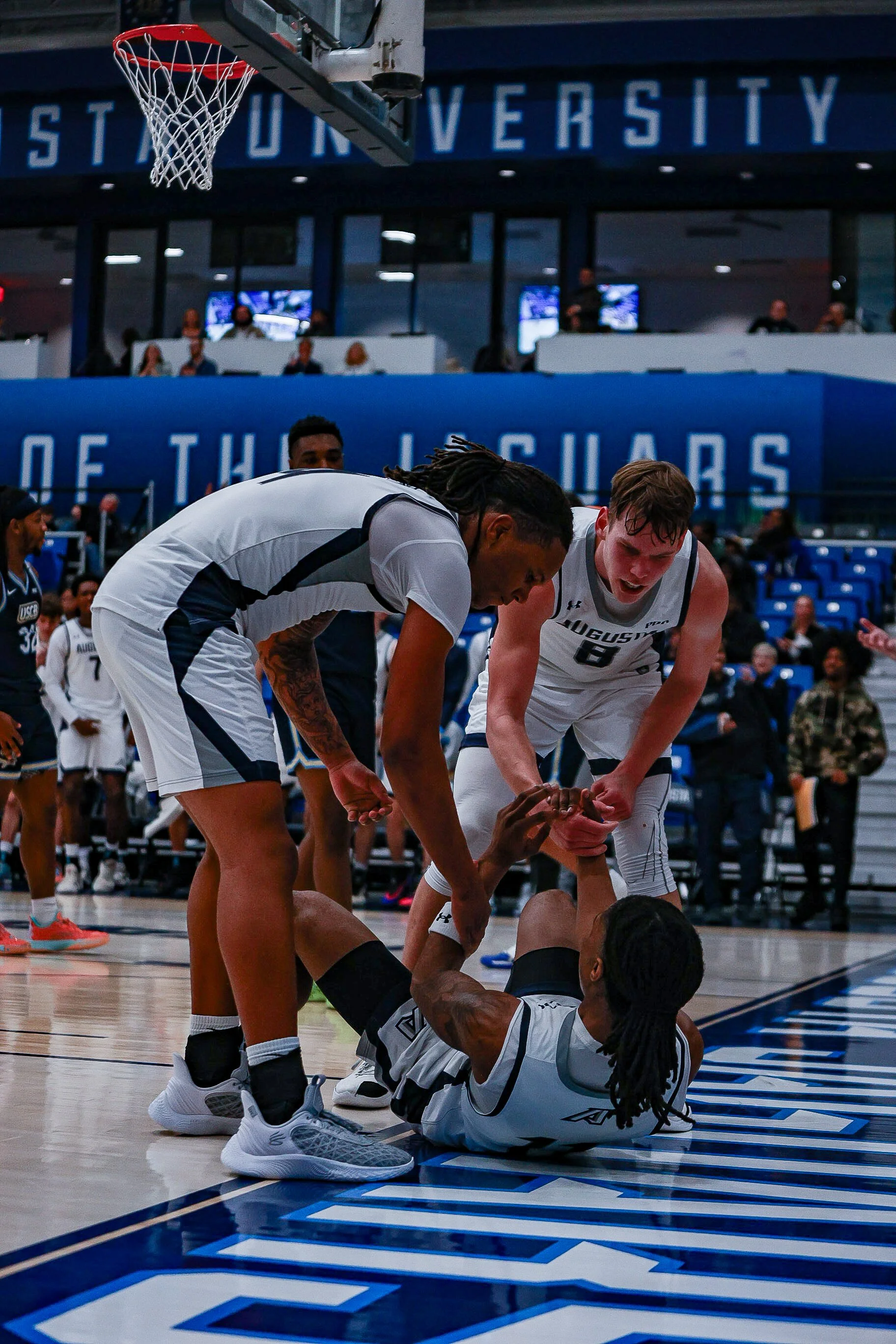  Kyndon Wilburg (on the floor) is helped up by DaRon Dumbar (left) and Elias Palsson (right) after a tough and-1 layup. (photo by Rodrigo Burgos Avila/the Bell Ringer) 