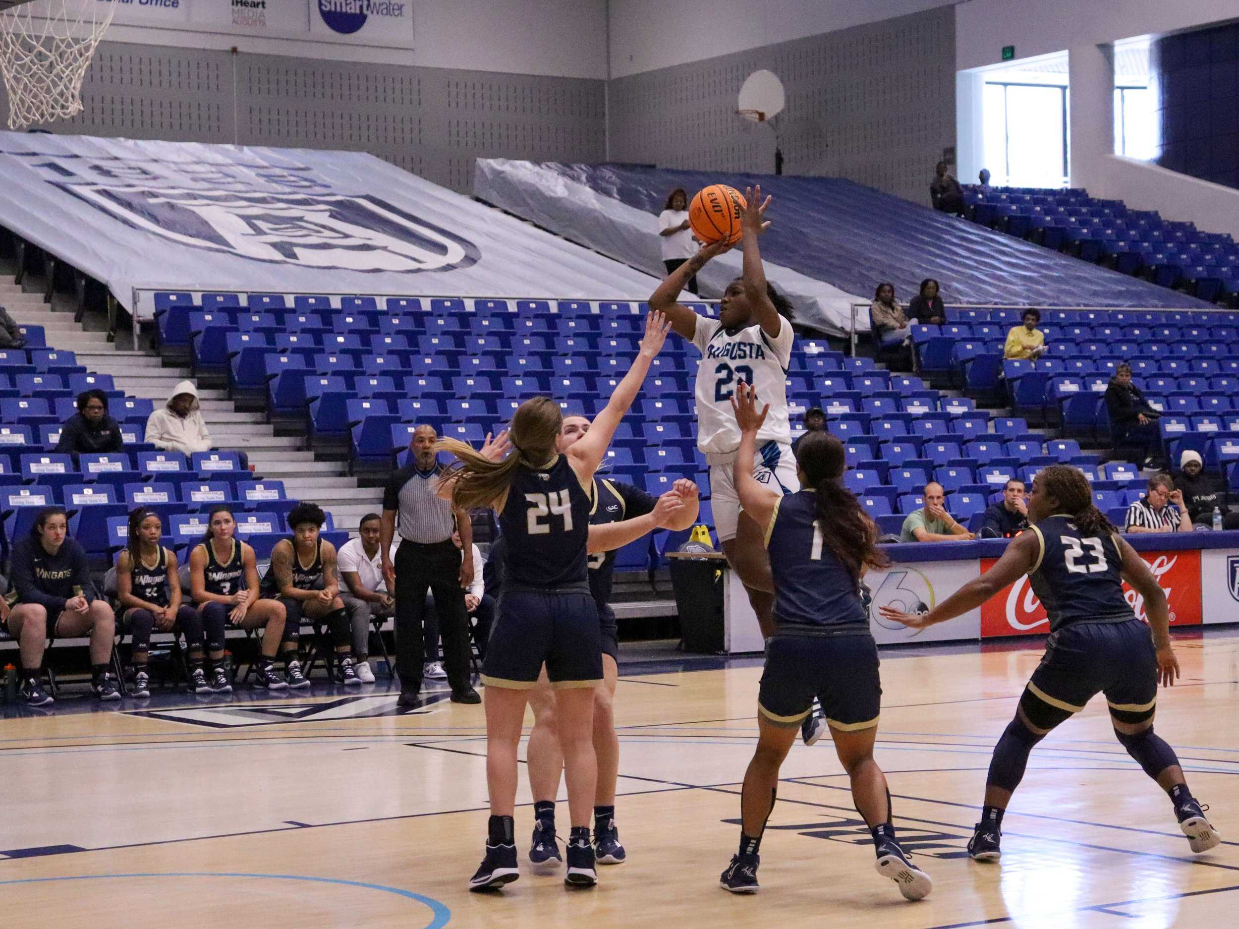   Shamaria Jennings (22) goes up for a jumper for the Augusta women’s basketball team against Wingate University. At the top of the page, Kennedi Manning scores two on a post move for AU. (photos by Madison Keel)  