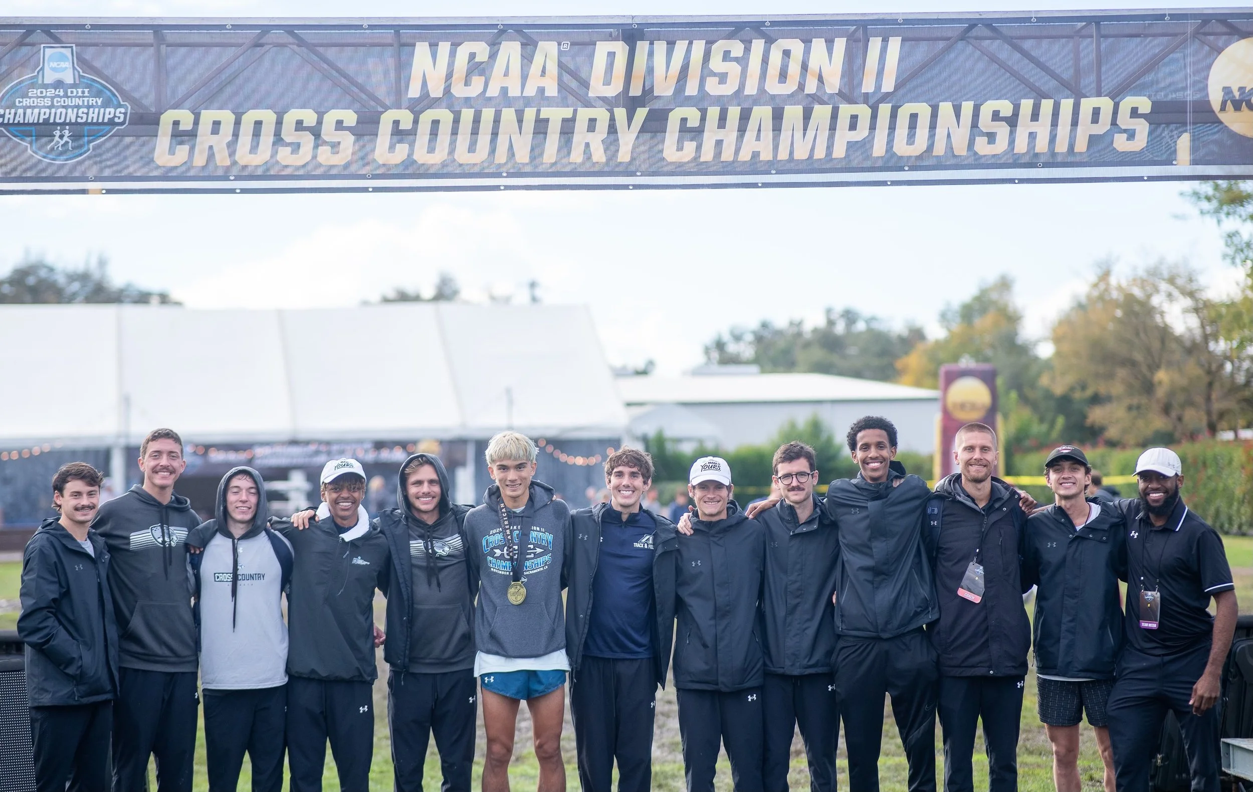  Jordan Robertson, AU’s first all-American in cross-country, wears his medal after finishing 32nd in the NCAA Division II championships in Sacramento, Calif. Joining him are teammates, from left to right: Thomas Rischar, Matthew More, Tripp Miller, Ani Tesfaye, Andrew Todd, Robertson, Brandon Martin, Patrick Motes, Avery Jaynes, Nasrudin Mohamed, Coach Jacob Burgamy, Assistant Coach Hans Troyer and Assistant Coach Churchill Ezeoknokwo. (photo courtesy of AU Athletics) 